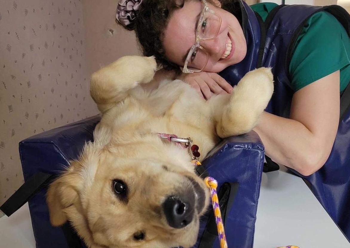 female staff member smiling and posing with golden retriever before x-ray female staff member smiling and posing with golden retriever before x-ray